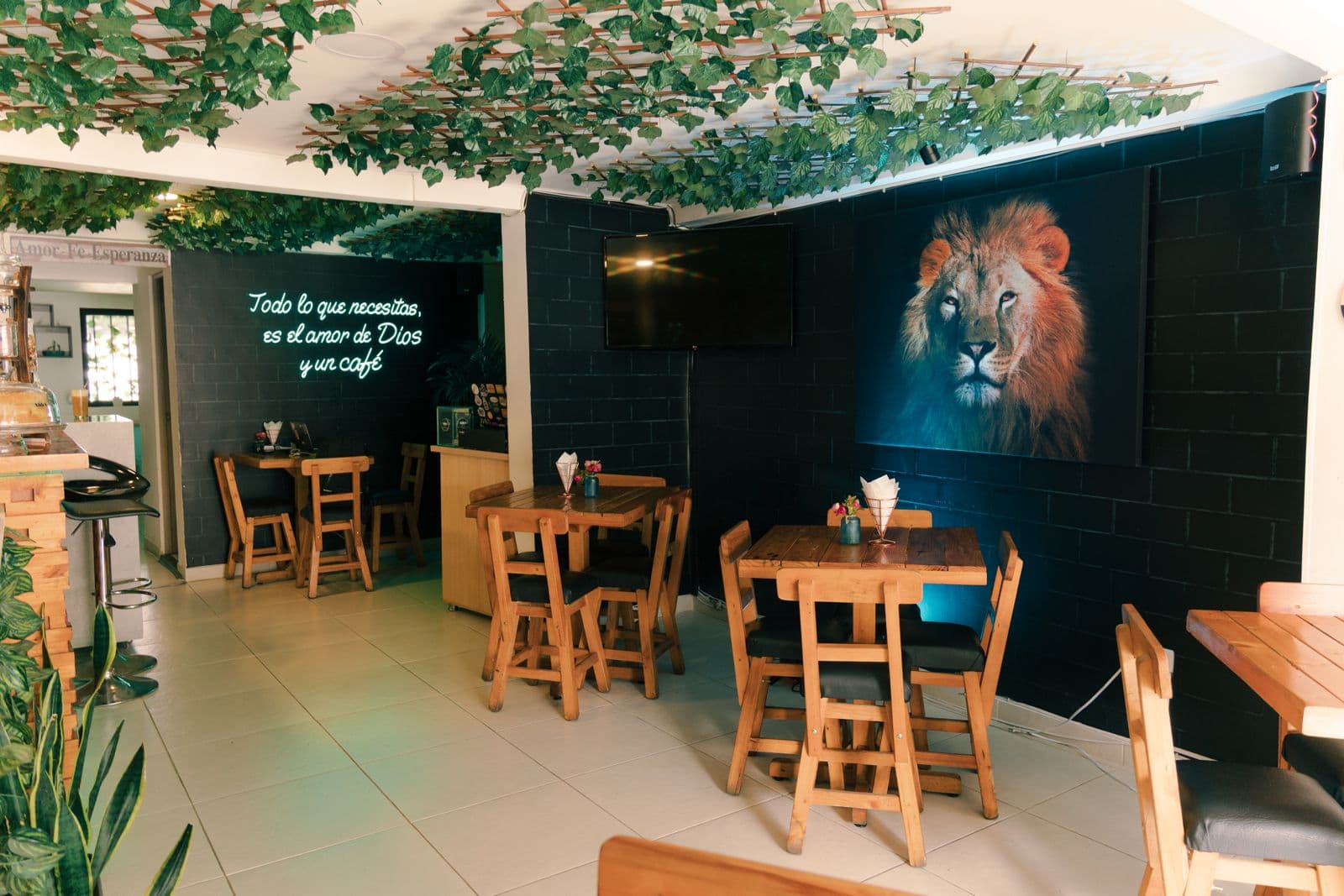 Salón principal con mural del León y neón 'Todo lo que necesitas es el amor de Dios y un café'