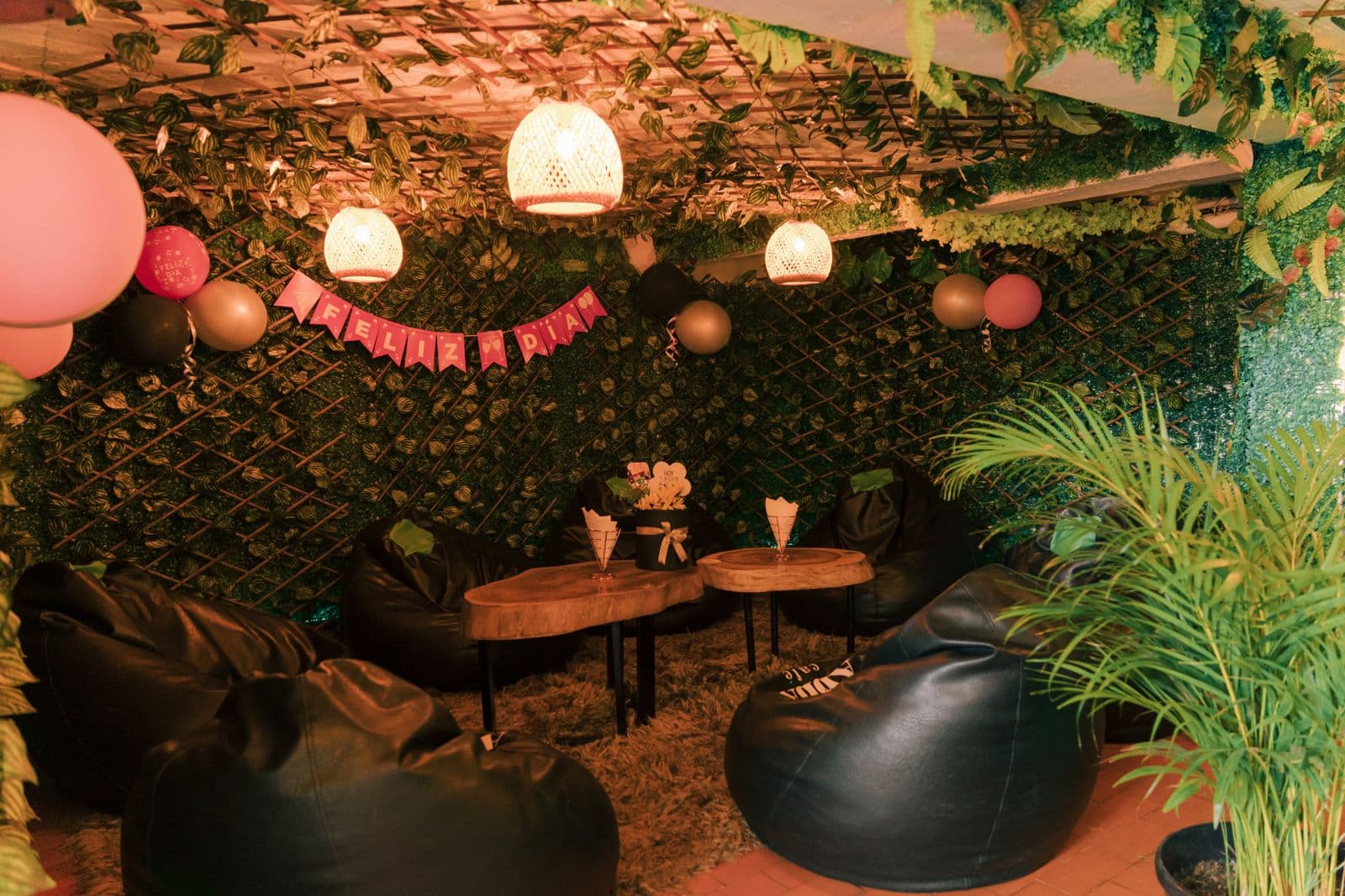 Lounge íntimo con puffs, lámparas de mimbre y pared de follaje